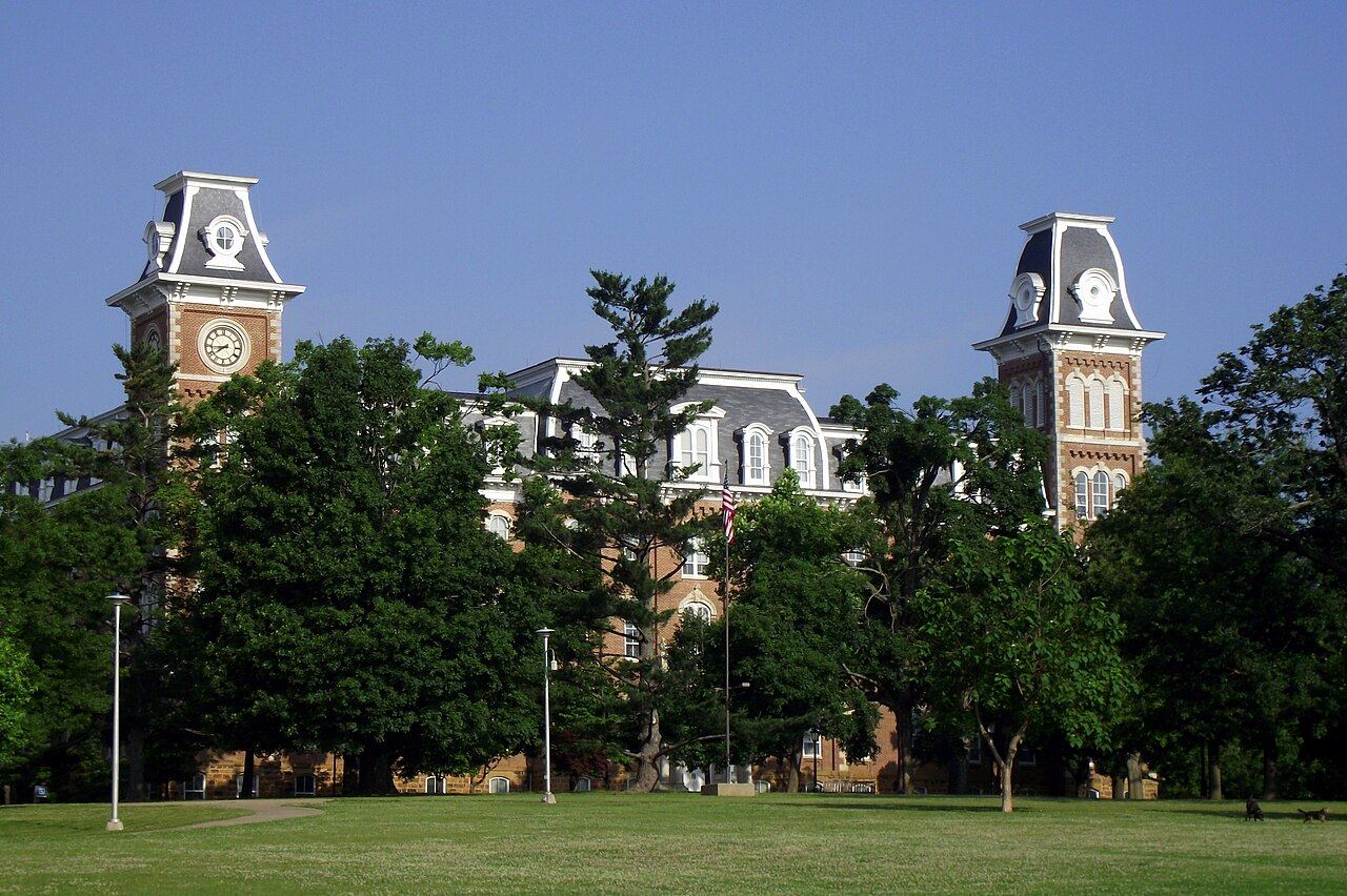 Old Main towers rising above trees and lawns in Fayetteville